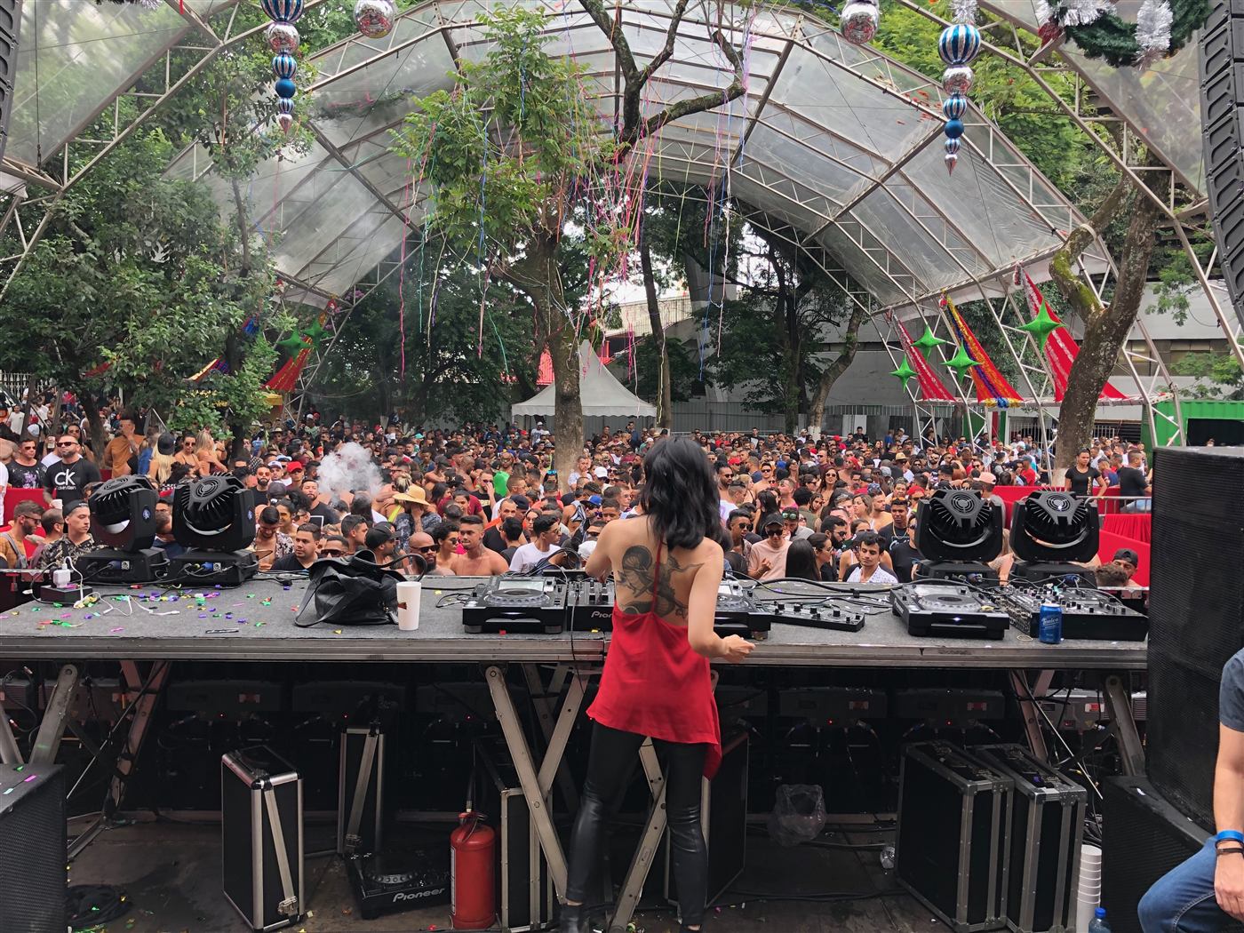 Festival com DJ e grande público em estufa de vidro, com som e iluminação