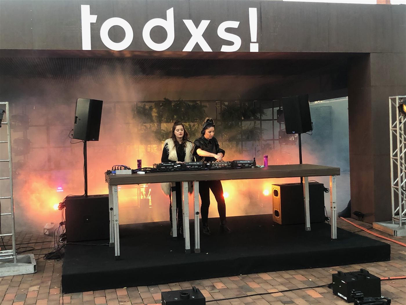 Palco com dupla de DJs, fumaça e iluminação cênica